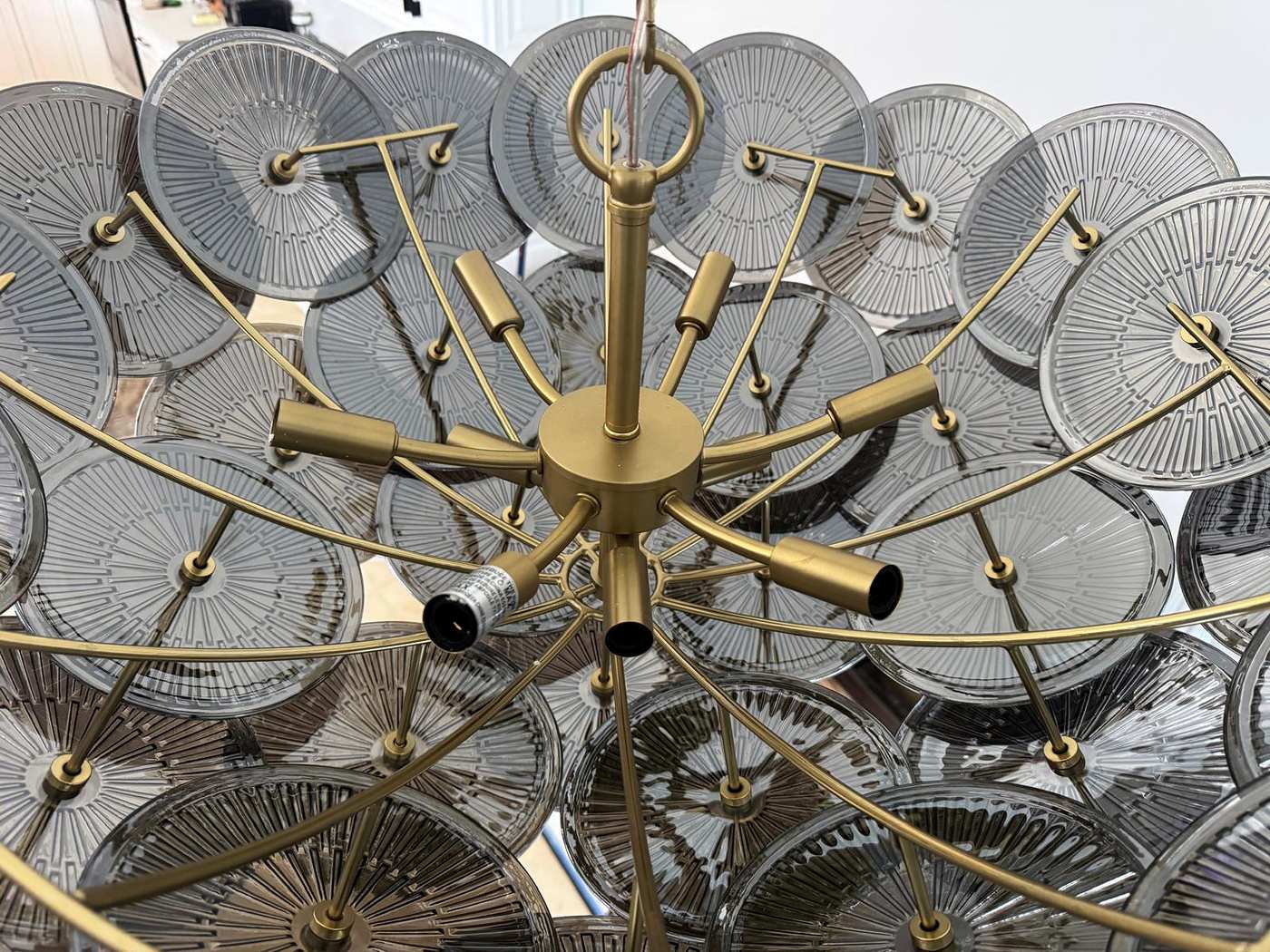 Looking up into a brass chandelier ringed with glass discs