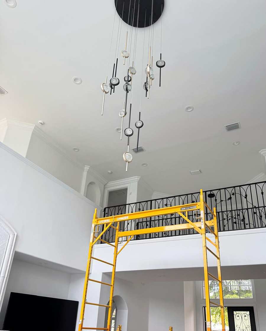 Chandelier hung in a tall entry, with rolling scaffolding set up below it