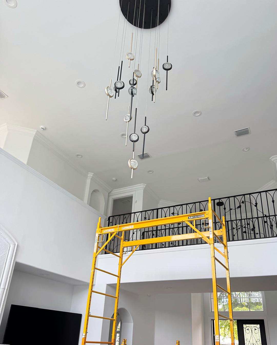 Chandelier hung in a tall entry, with rolling scaffolding set up below it