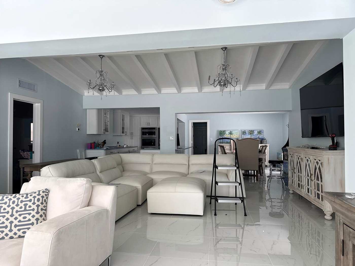 Two crystal chandeliers in a living room with a white beamed ceiling
