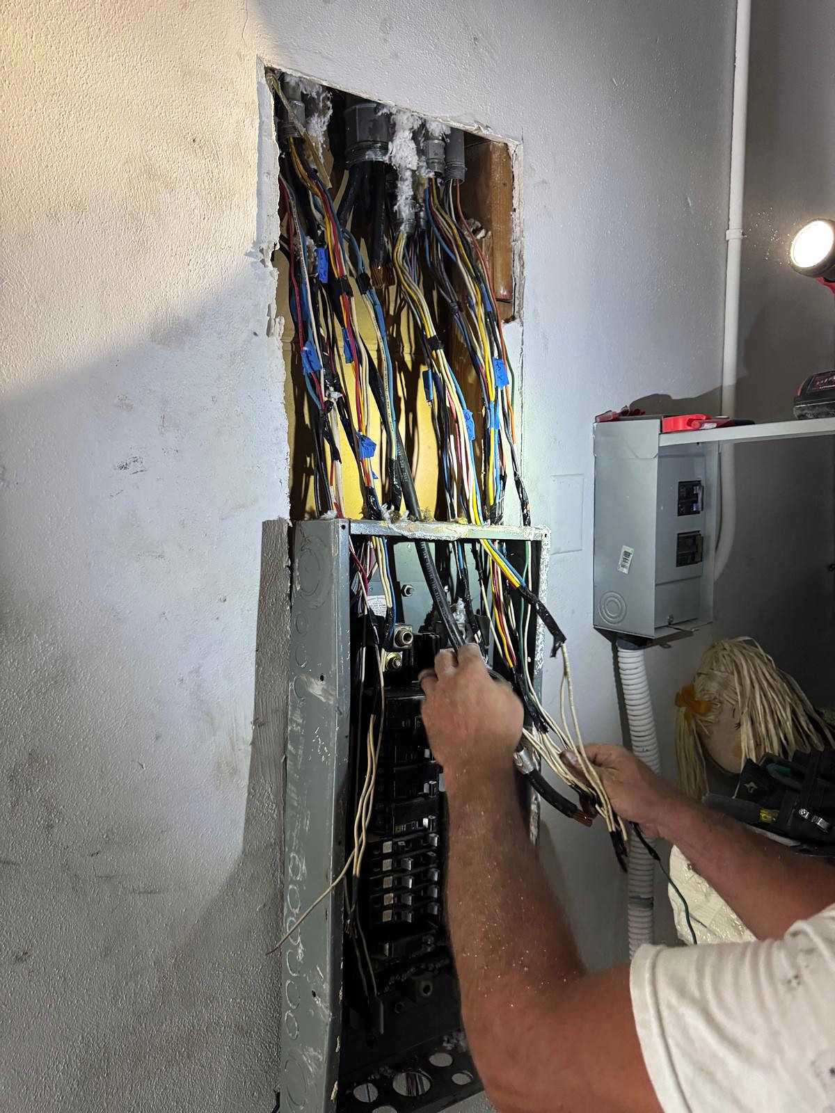 An electrician's hands sorting circuit wires into a new panel