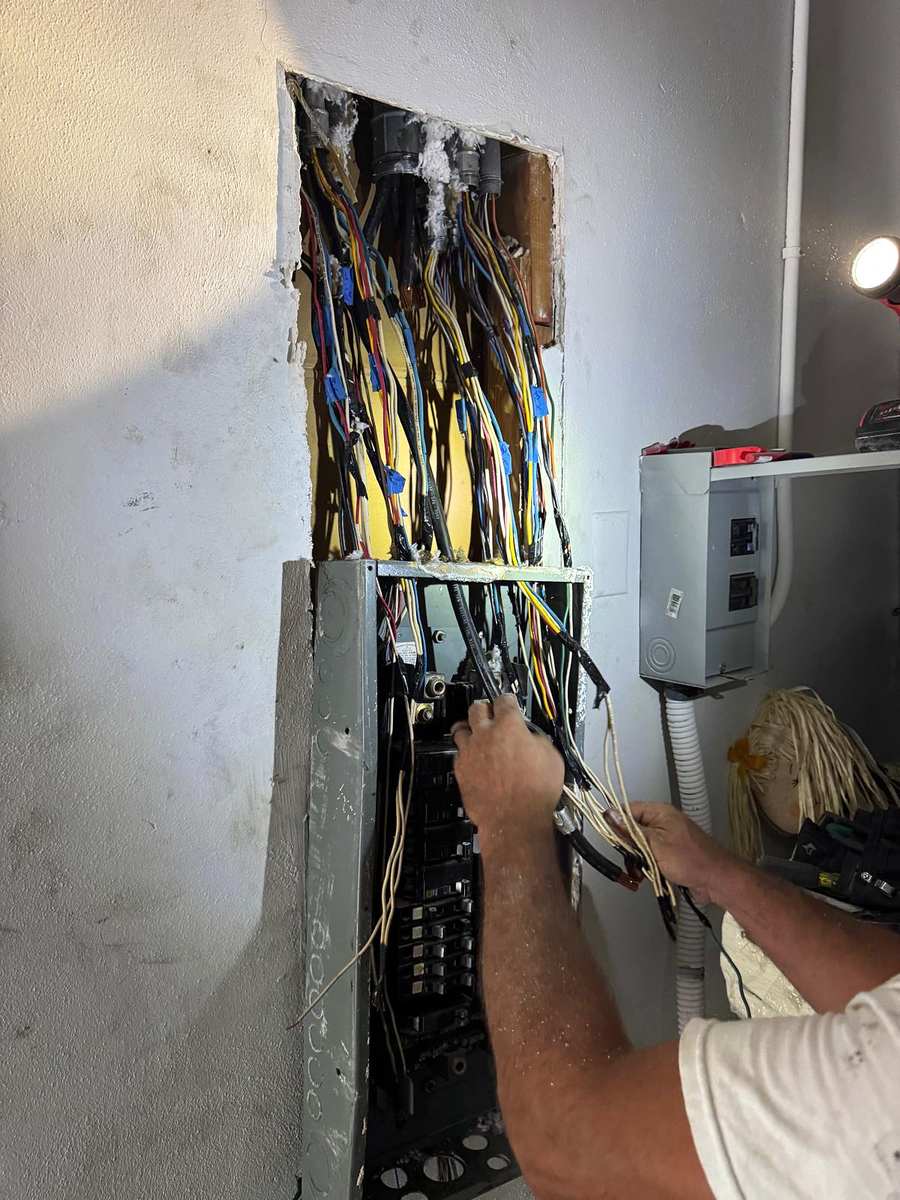 An electrician's hands sorting circuit wires into a new panel