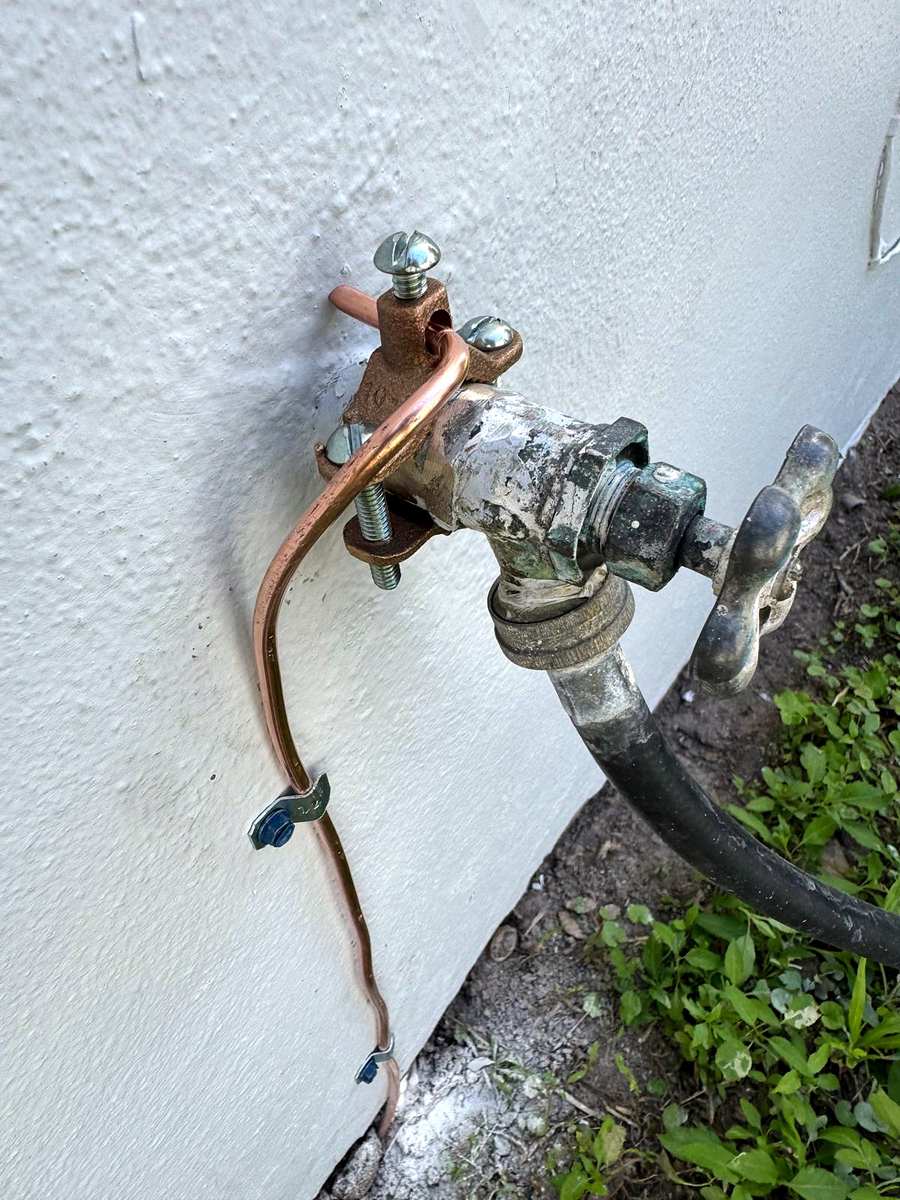 Copper bonding wire clamped to a pipe on an outside wall