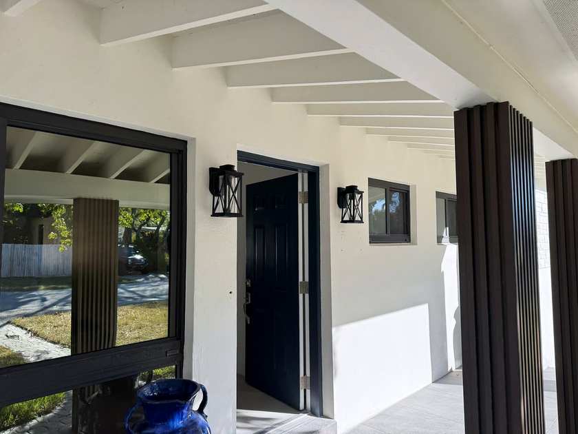 Covered porch with black wall lanterns beside the entry door