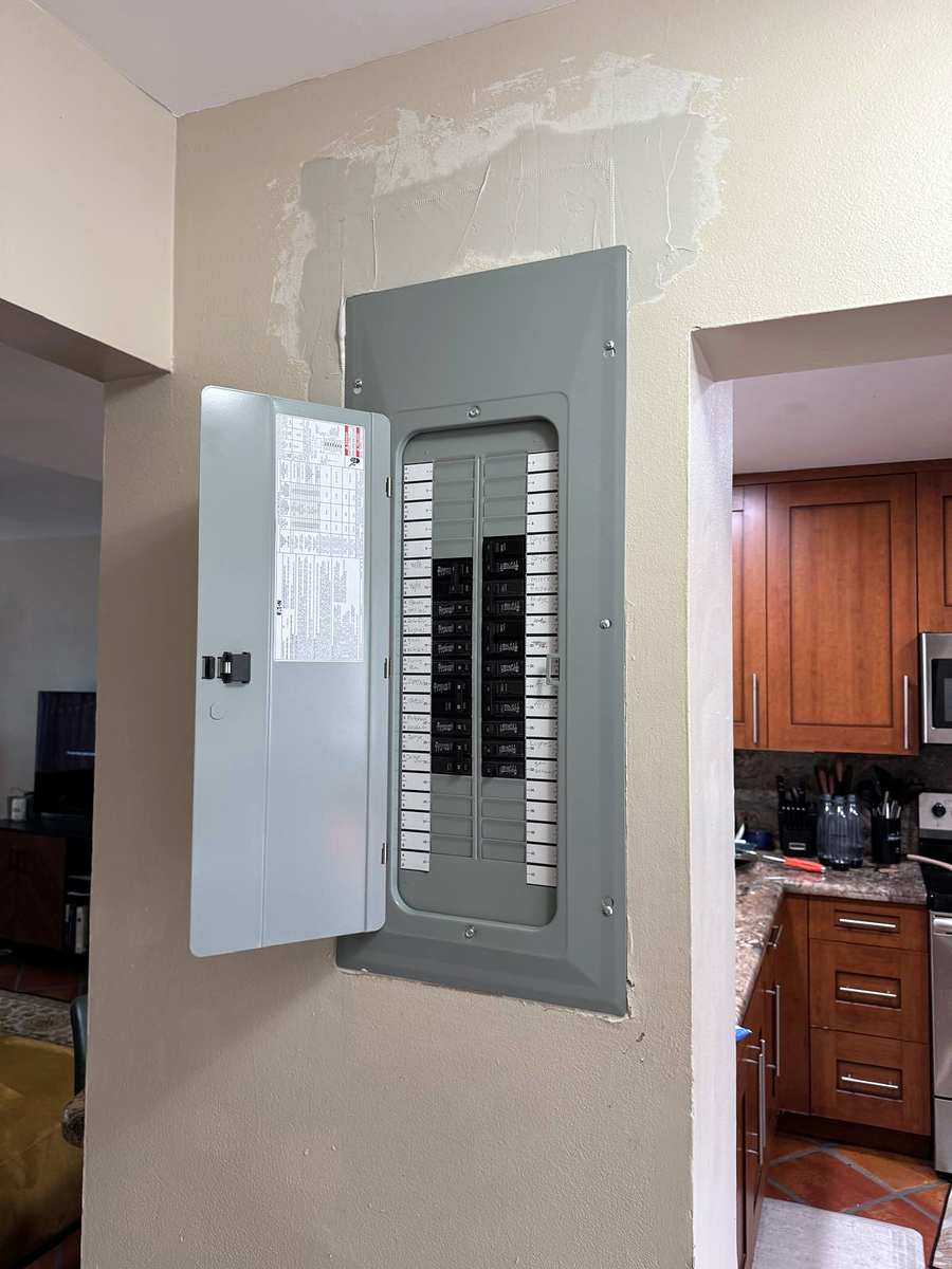 The same wall beside the kitchen with the finished panel, door open and circuits labeled