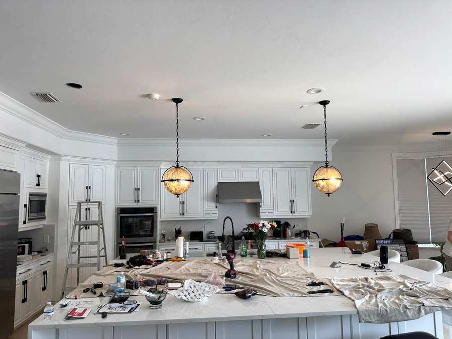 Two globe pendants over a kitchen island during an install, drop cloths on the counter